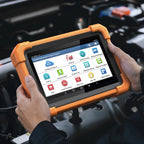 a person's hands holding a LAUNCH Creader Professional 919 Expert diagnostic tablet over an open car engine bay. The device is enclosed in a rugged orange protective bumper and features a touchscreen displaying various automotive diagnostic menu icons.